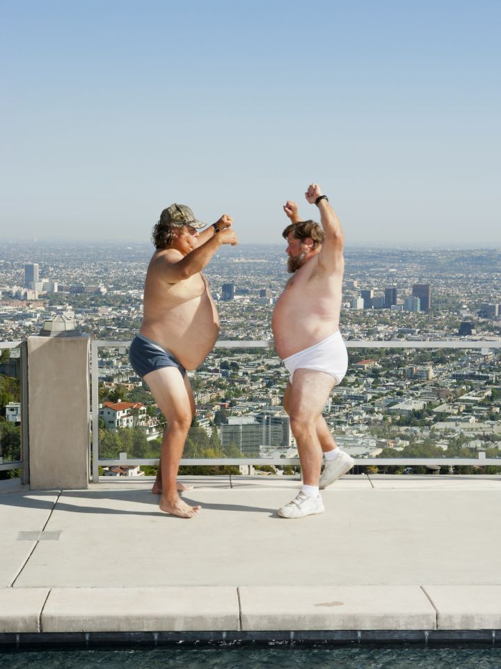 Das Foto zeigt zwei dicke Männer in Unterhose, die tanzen.