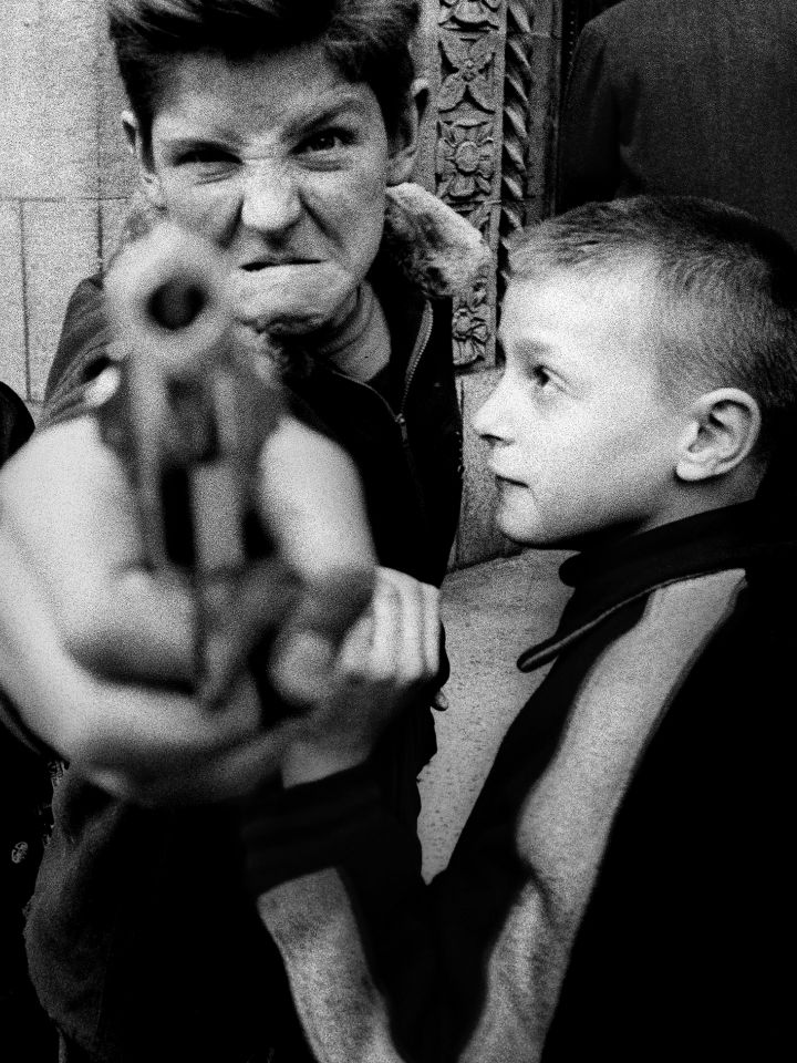 Das Foto ist in schwarzweiß und zeigt zwei Kinder. Ein Kind hält eine Pistole.