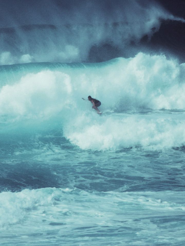 Ein Surfer zwischen hohen, stürmischen Wellen.