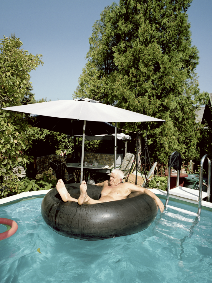 Ein alter Mann sitzt in einem Schwimmring in einem Gartenpool.