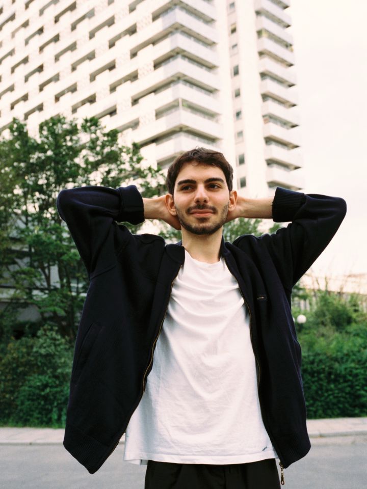 Ein Portraitfoto von Enes Şahin vor einem Hochhaus.