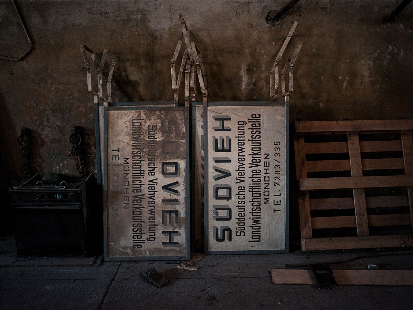 Zwei Schilder mit der Aufschrift Südvieh lehnen neben einer Europalette an der Wand.