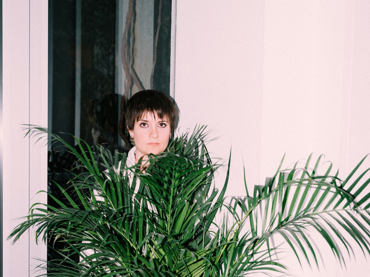 Christina Tscharyiski im weißen Einteiler hinter einer Palme.