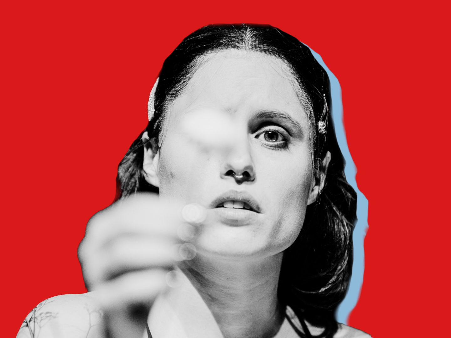 Eine Frau hält mit ernstem Gesicht eine Blume in die Kamera.