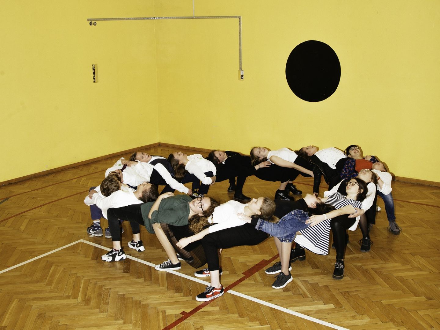Das Foto zeigt eine Gruppe Jugendlicher, die sich nach hinten auf die jeweils andere Person lehnen und dadurch einen Kreis bilden.
