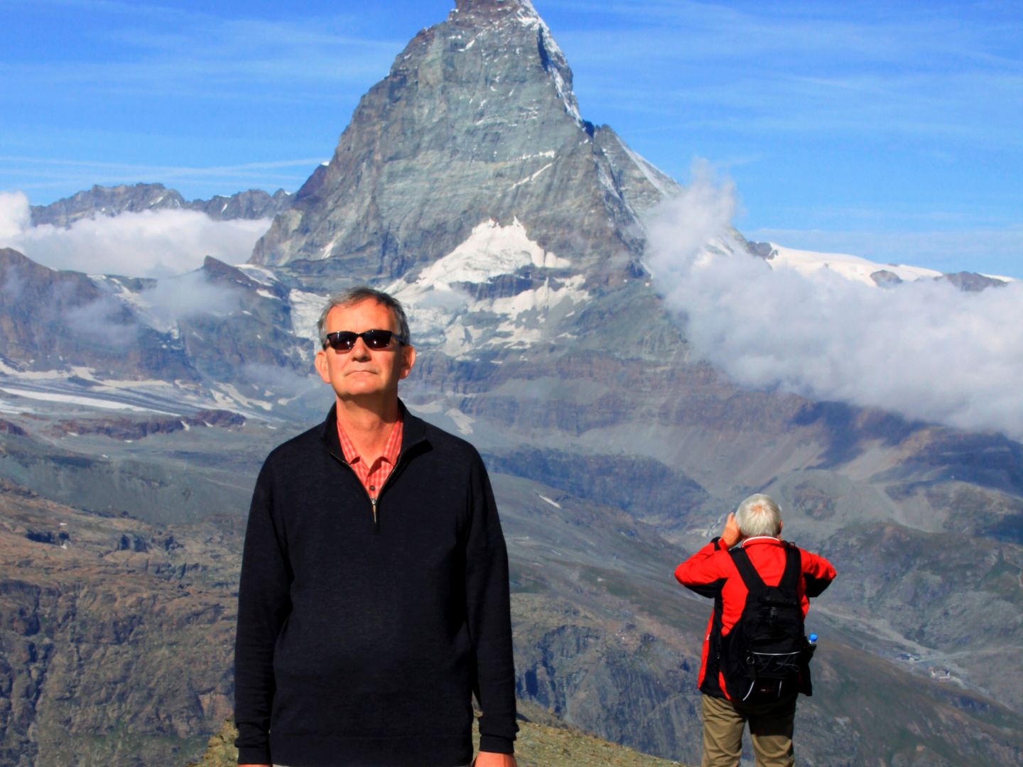 Das Foto zeigt einen Mann mit Hund vor Bergpanorama