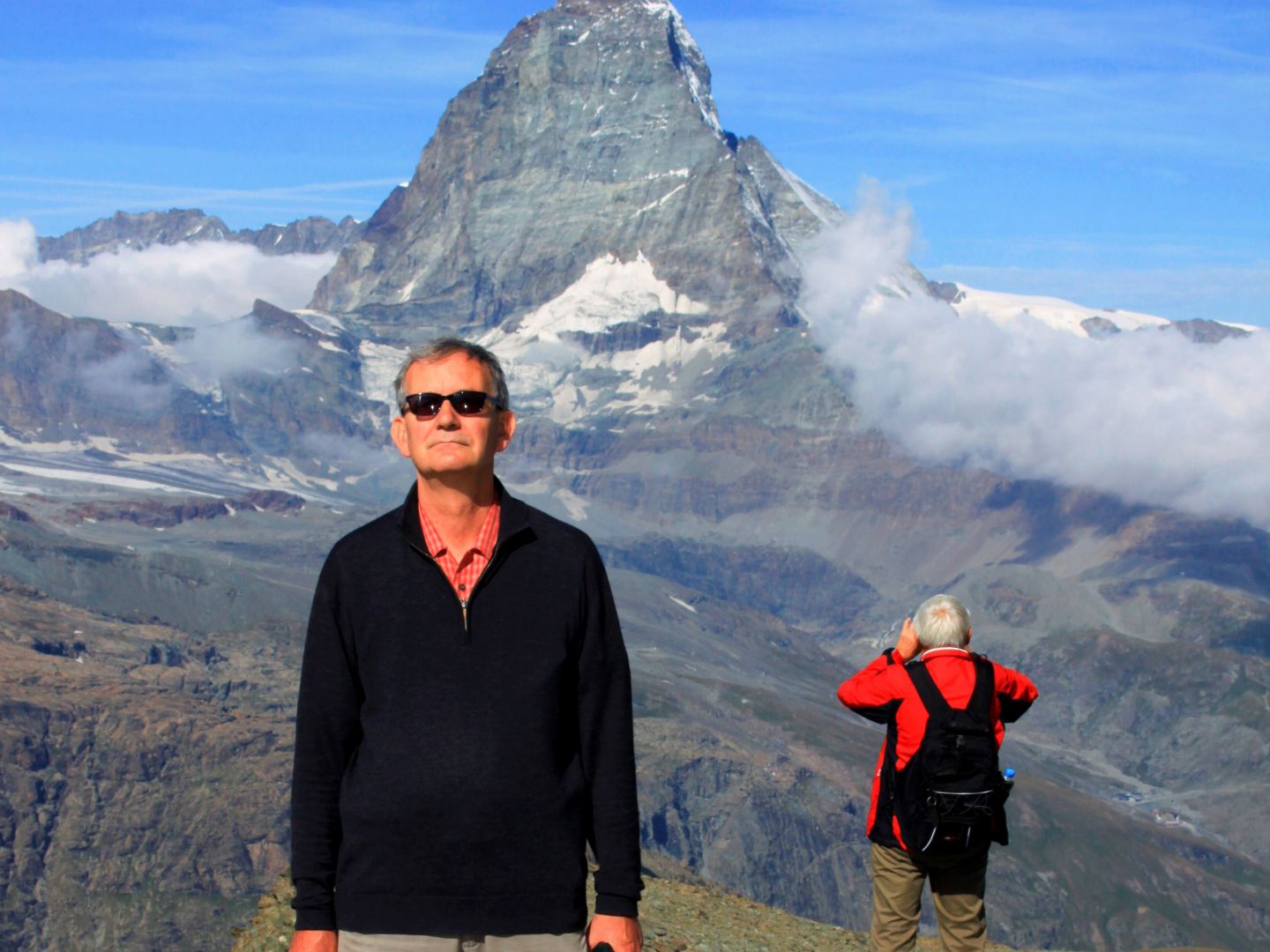 Das Foto zeigt einen Mann mit Hund vor Bergpanorama