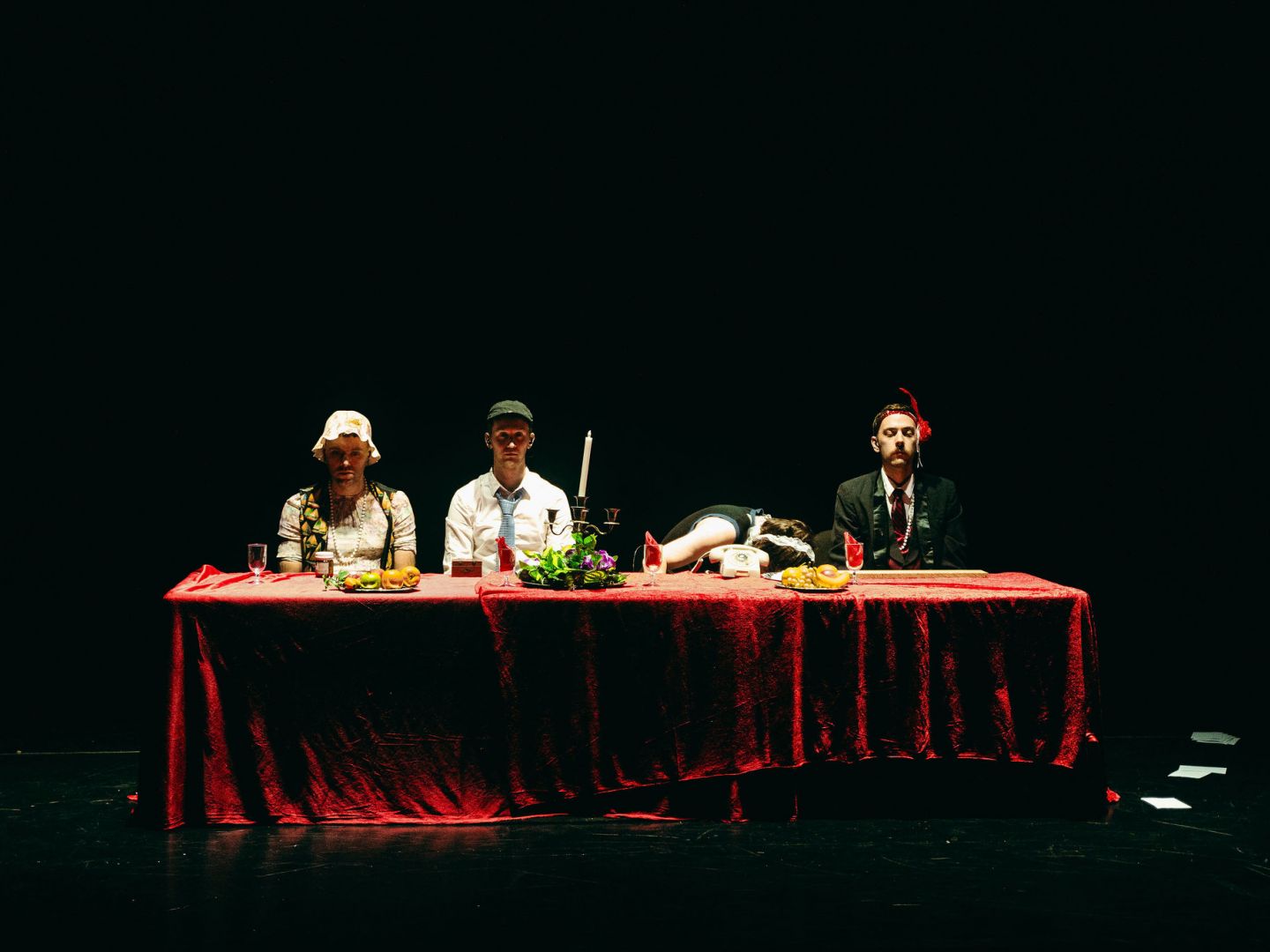 Vier Darsteller sitzen an einem Tisch mit roter Tischdecke