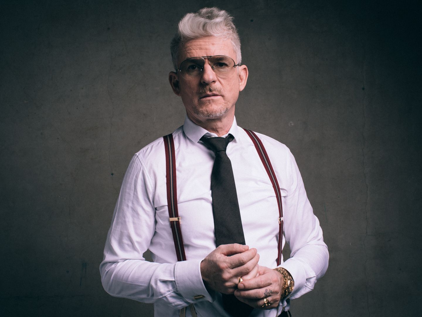 Ein Portraitfoto von Dennis Dirksen stehend von einer grauen Wand