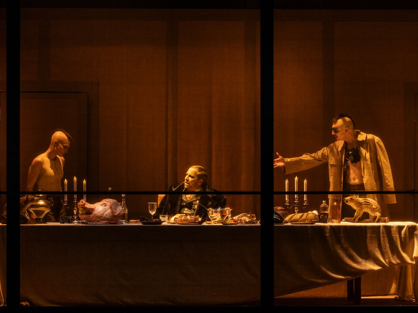 Drei Schauspieler*innen an einer reich geschmückten Tafel.