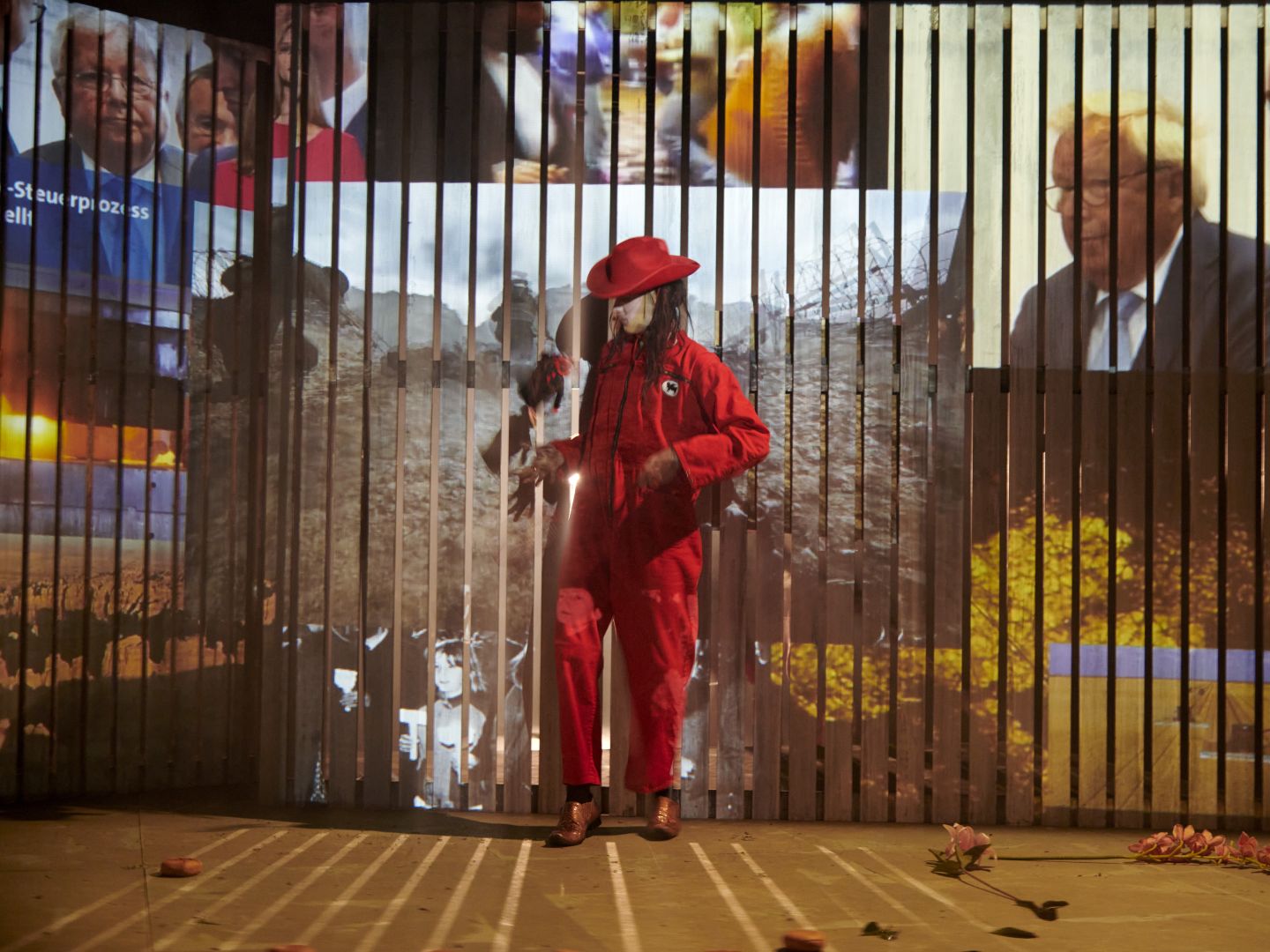 Ein in rot gekleideter Cowboy vor einer mit Videoprojektionswand.