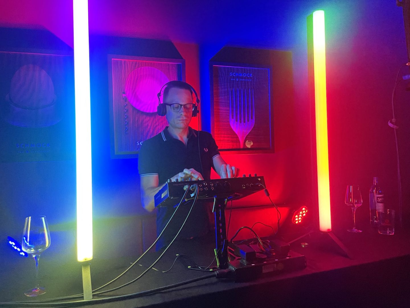 DJ Modeptobias am DJ Pult, neben ihm erleuchten 2 bunte Neonröhren das Pult