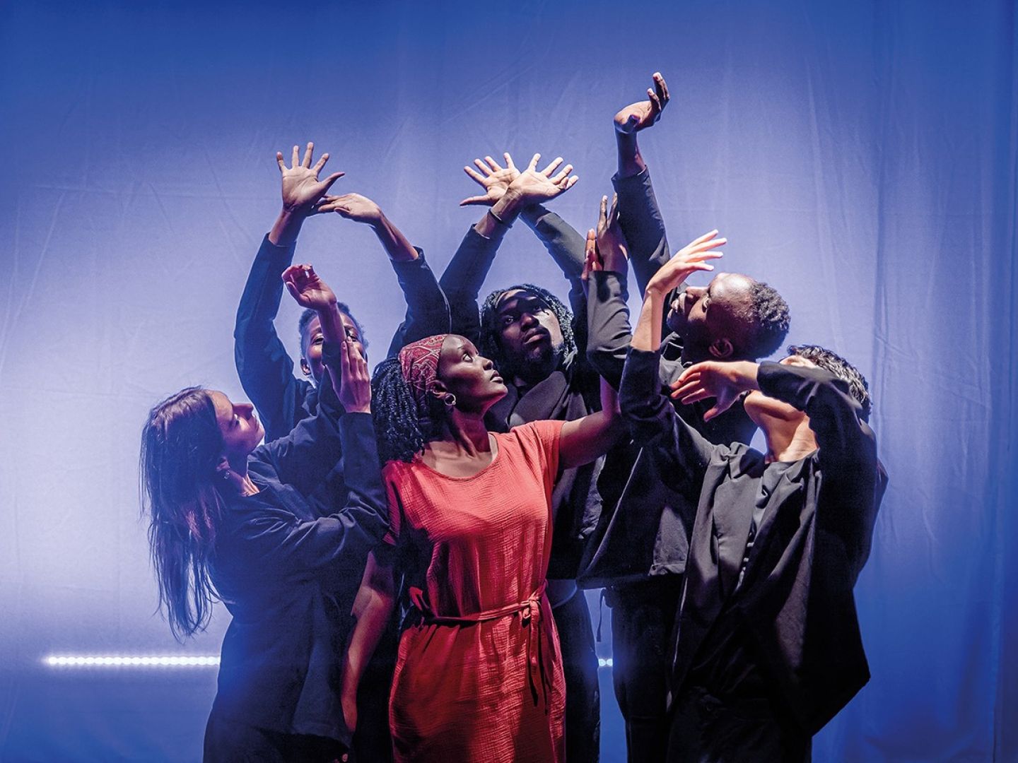 Das Ensemble von Theater Grenzenlos hebt im Pulk die Arme.