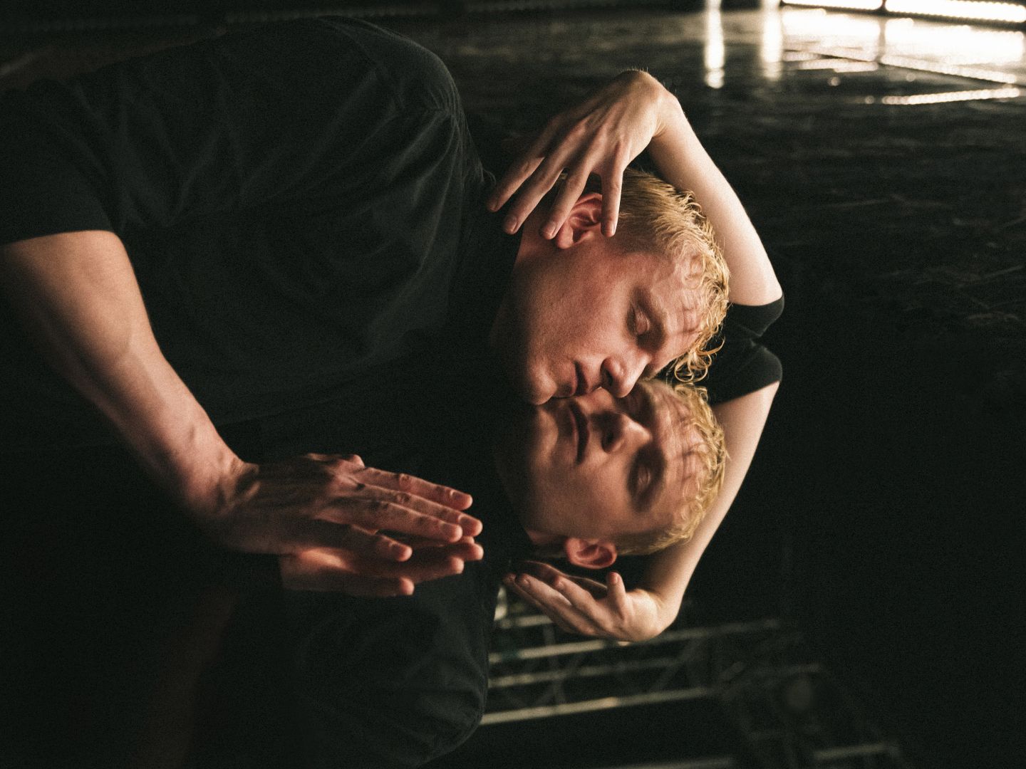 Ein Schauspieler spiegelt sich liegend im Boden.