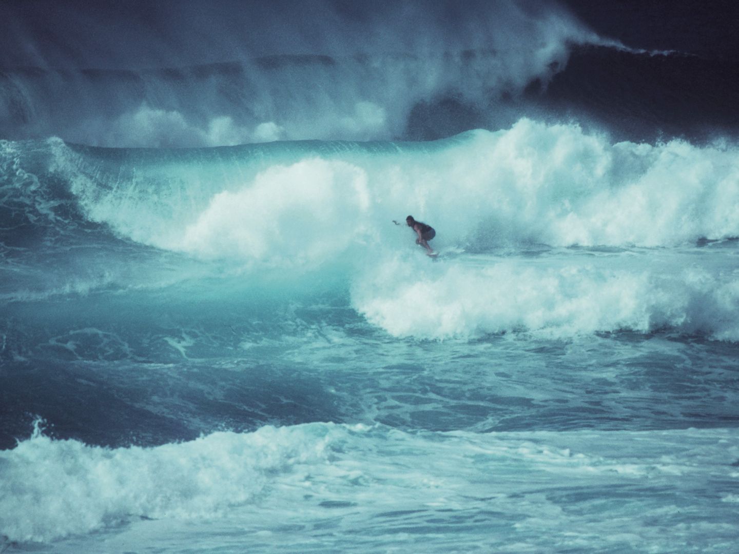 Ein Surfer zwischen hohen, stürmischen Wellen.