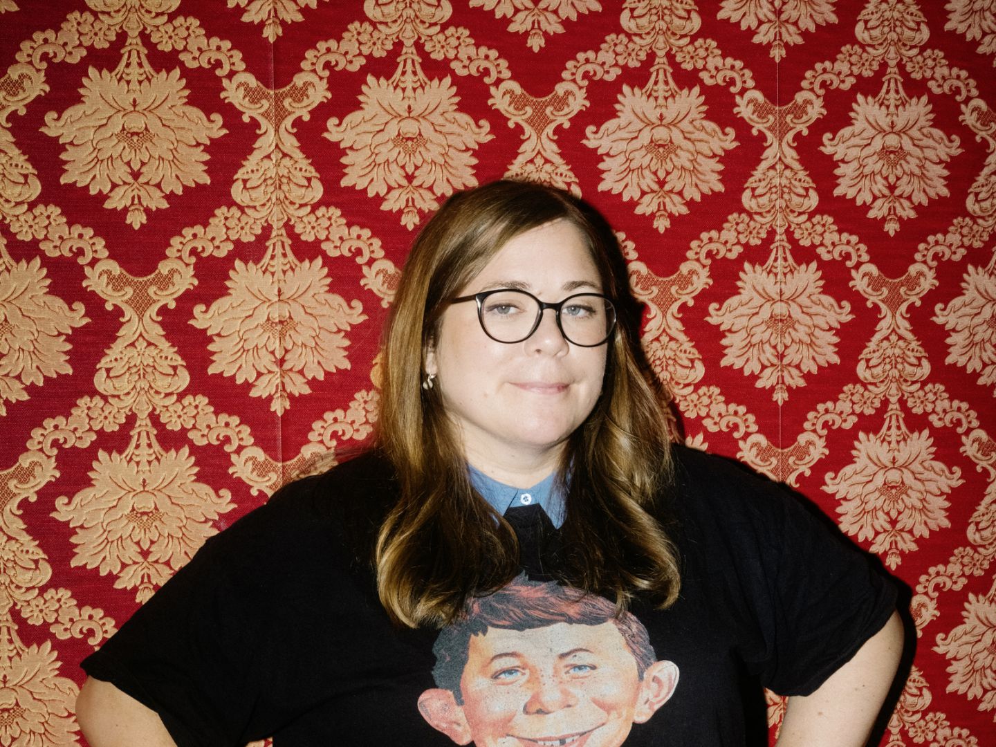 Stefanie Sargnagel vor einer roten Tapete. Auf ihrem T-Shirt steht "MAD" unter dem Kopf eines Jungen.
