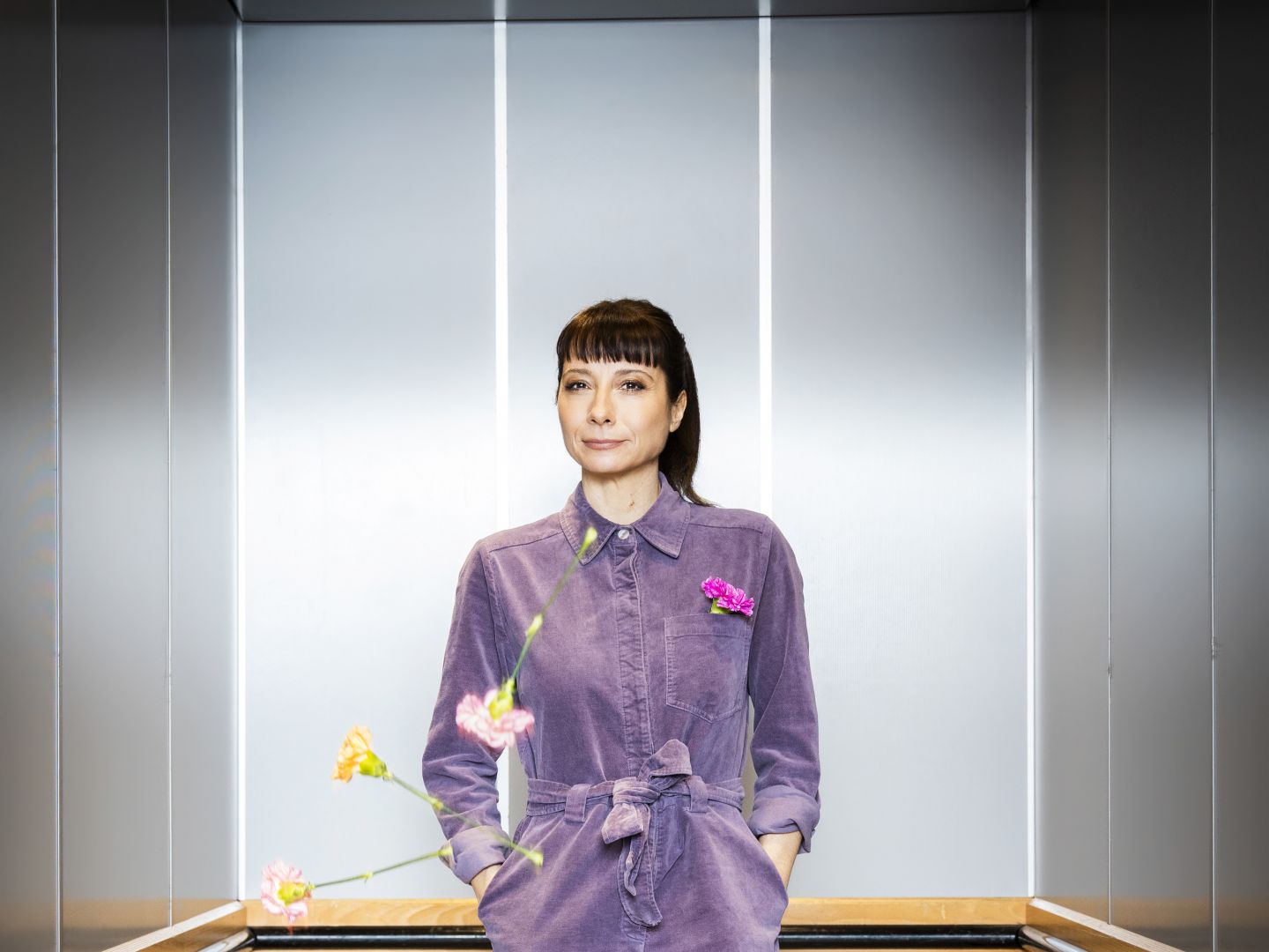 Nina Sonnenberg in einem Aufzug. Blumen fallen von der Decke.