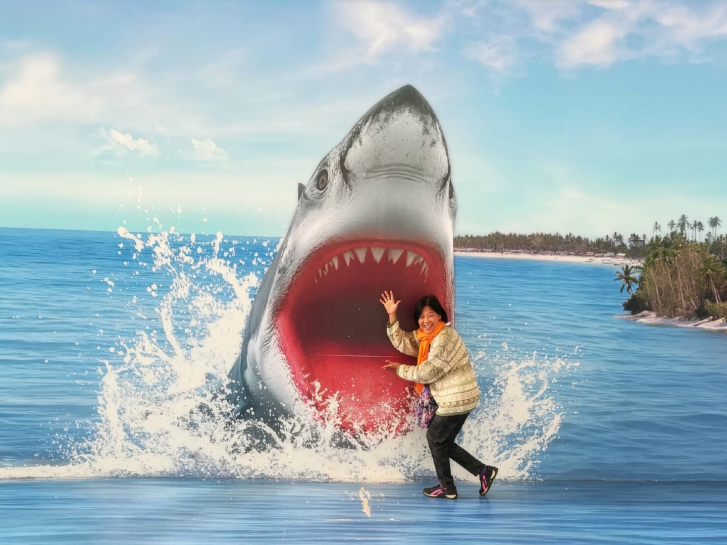 Eine Frau steht vor einer Fotowand mit einem Hai, der aus dem Wasser springt.