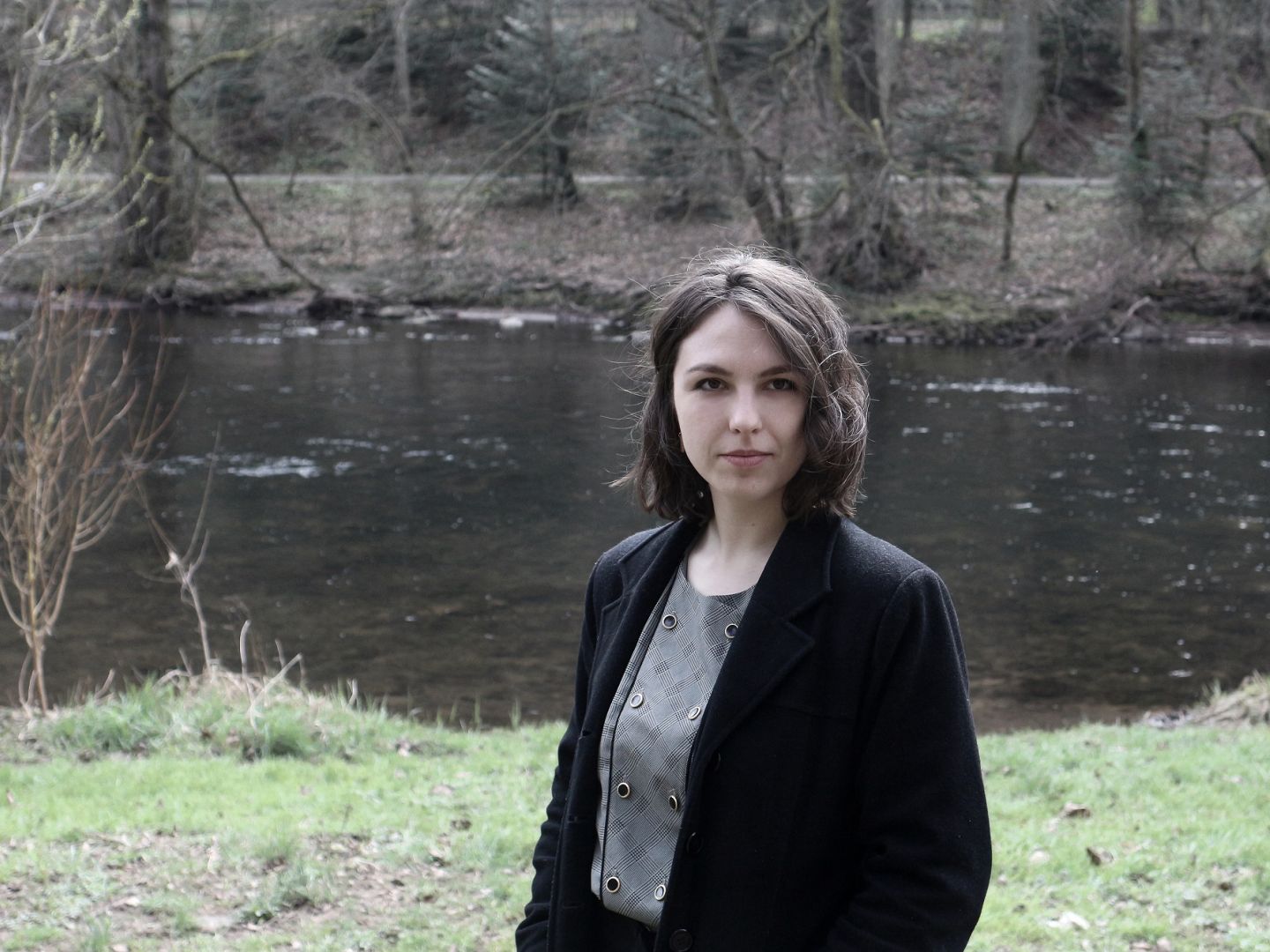 Das Foto zeigt Sonja Hoyler in einem Wald vor einem Fluss