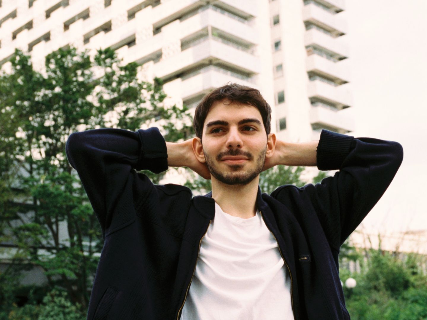 Ein Portraitfoto von Enes Şahin vor einem Hochhaus.