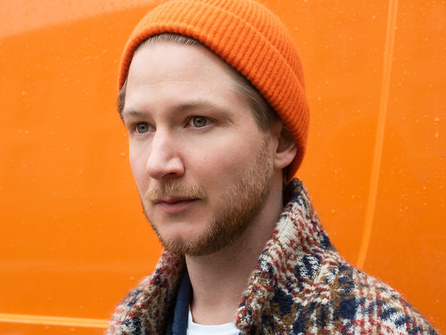 Ein Portraitfoto von Mats Süthoff vor orangenem Hintergrund.