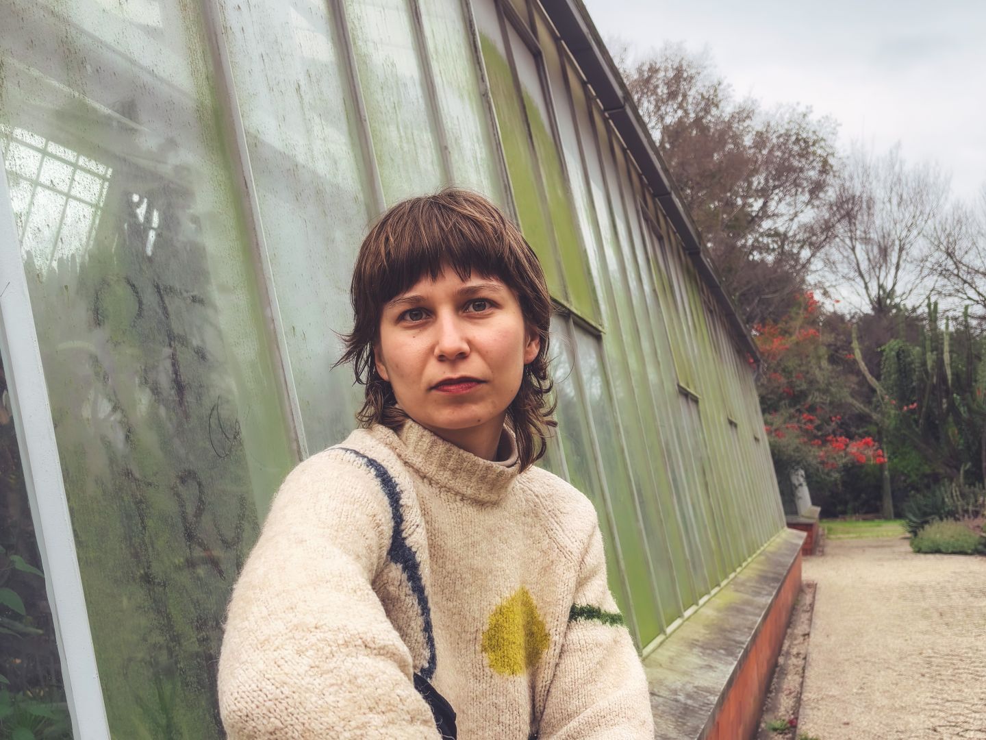 Ein Portraitfoto von Veronika Müller-Hauszer vor einem Gewächshaus.