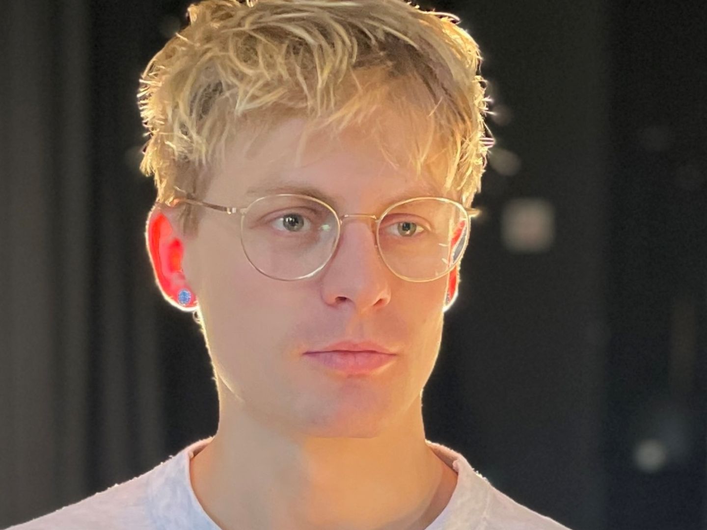 Person mit kurzen blonden Haaren und einer Brille. 