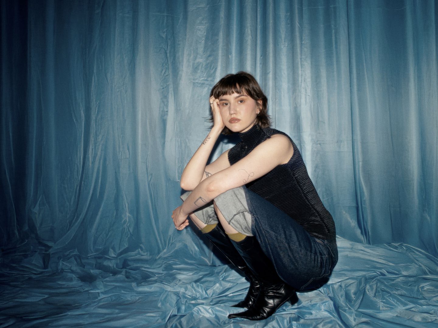 Maja Beyer sitzt in der Hock vor einem blauen Vorhang.