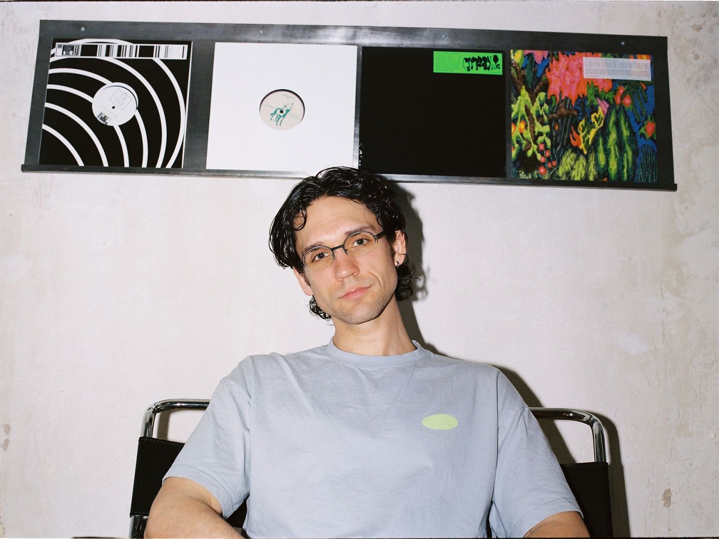 Matthias Schubert sitzt vor einer Wand, an der Platten aufgehängt sind.