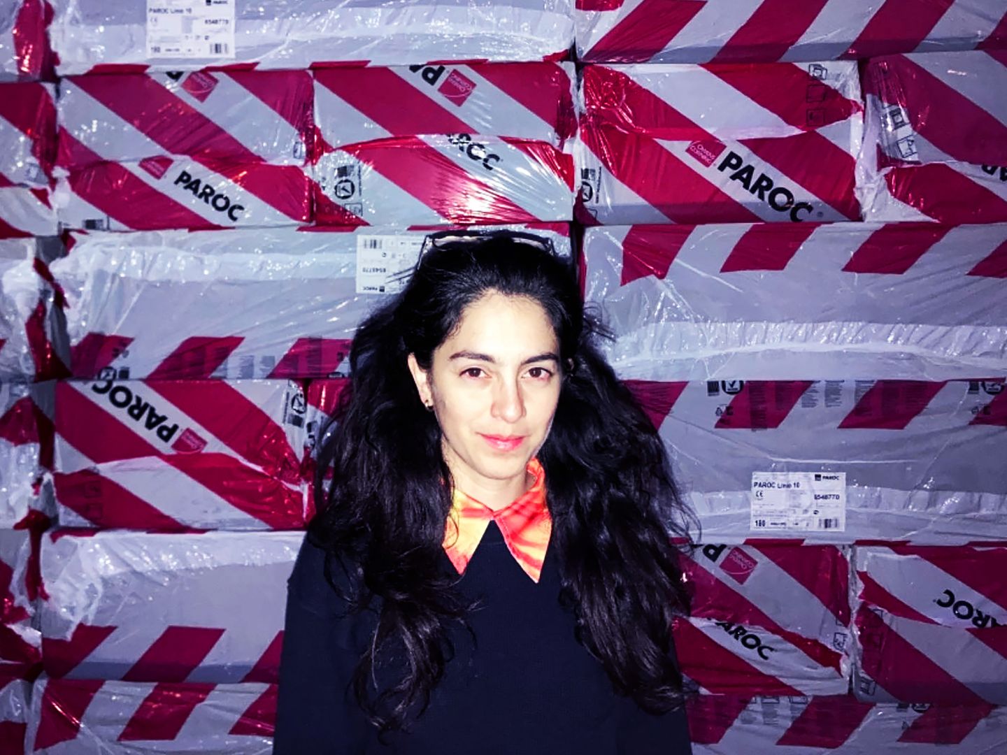 Daniela Zorrozua steht vor Paketen, die in einer rot-weißen Plane verpackt sind.