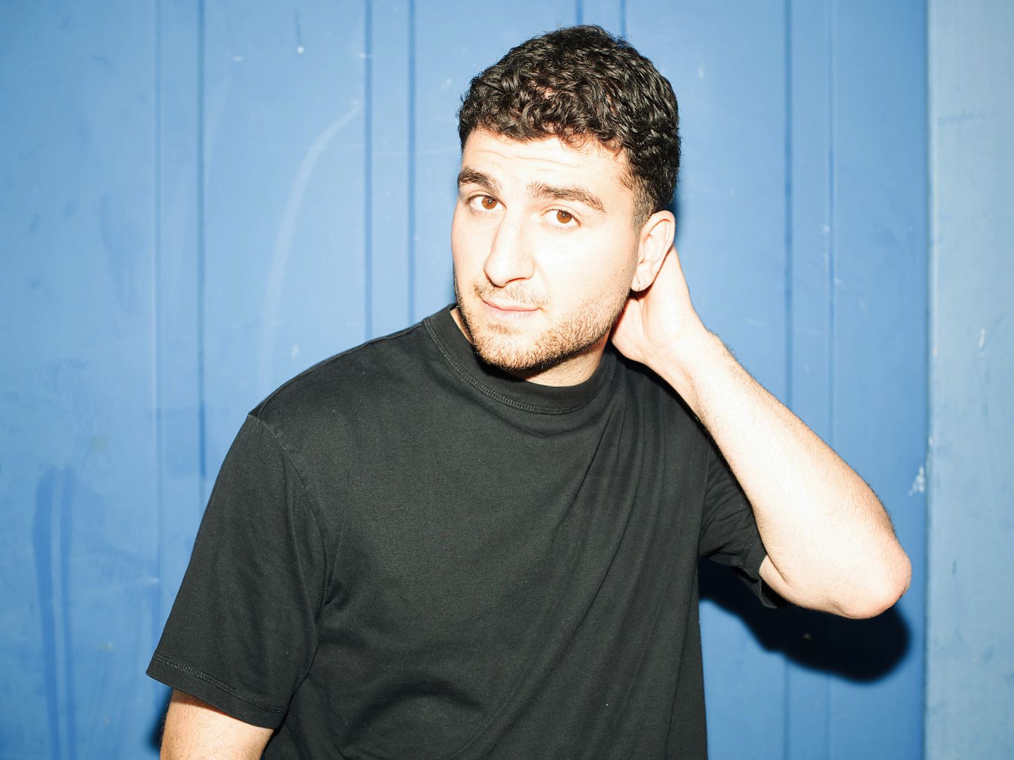 Portraitfoto von Baran Sönmez vor blauem Hintergrund