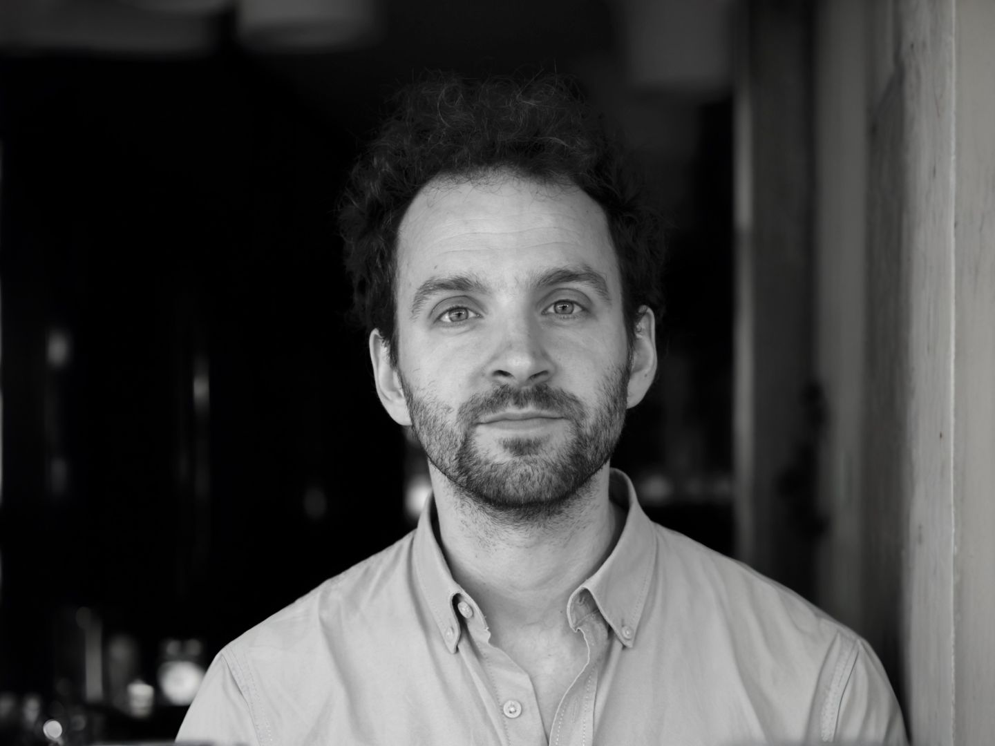 Ben Roessler steht vor einem Türeingang und blickt in die Kamera.