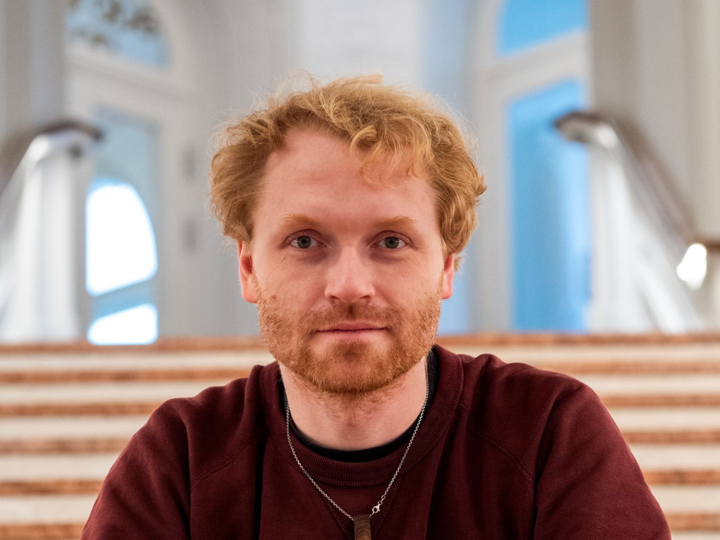 Ein Portraitfoto von Fiete Wachholtz auf einer großen Treppe.