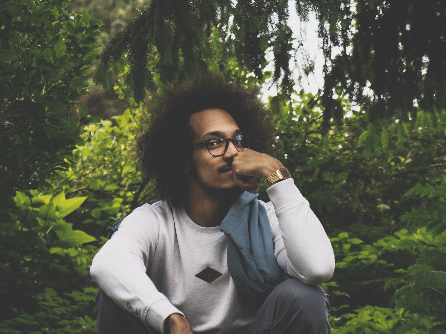 Portraitfoto von Friedrich Byusa Blam hockend in einem Wald.