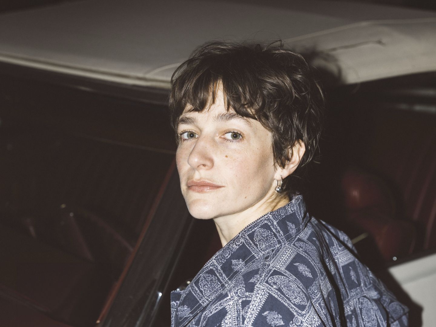 Portraitfoto von Luisa Wandschneider vor einem weißen Auto.