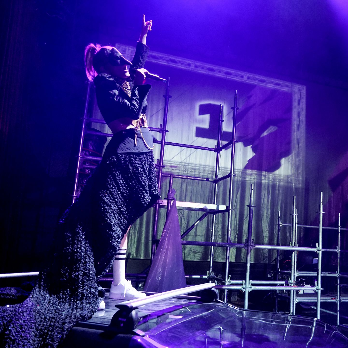 Das Bild zeigt die Rapperin Antifuchs, die vorne singt und einen Arm in die Luft streckt.