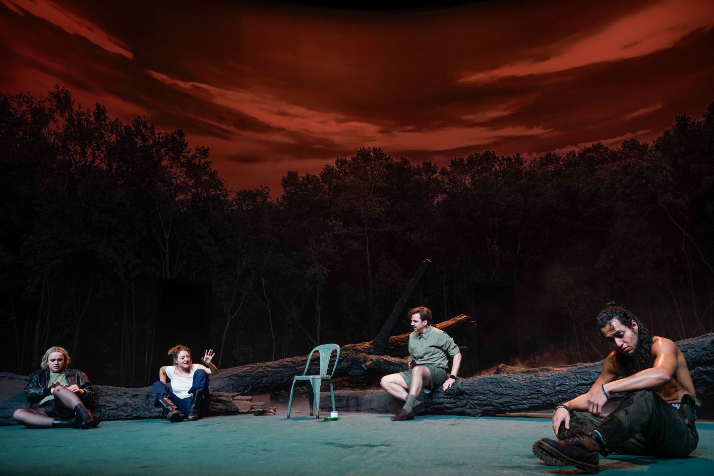 Lasse Stadelmann, Lola Dockhorn, Pascal Fligg und Jawad Rajpoot sitzen erschöpft und niedergeschlagen auf dem Boden. Der Himmel im Hintergrund ist rot verfärbt.