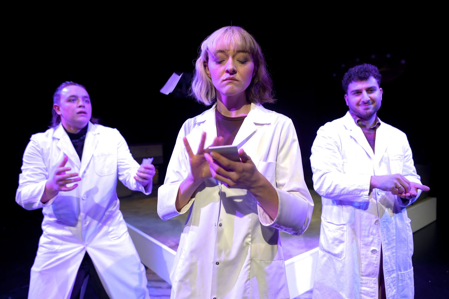 Drei Schauspieler*innen in weissen Kitteln.