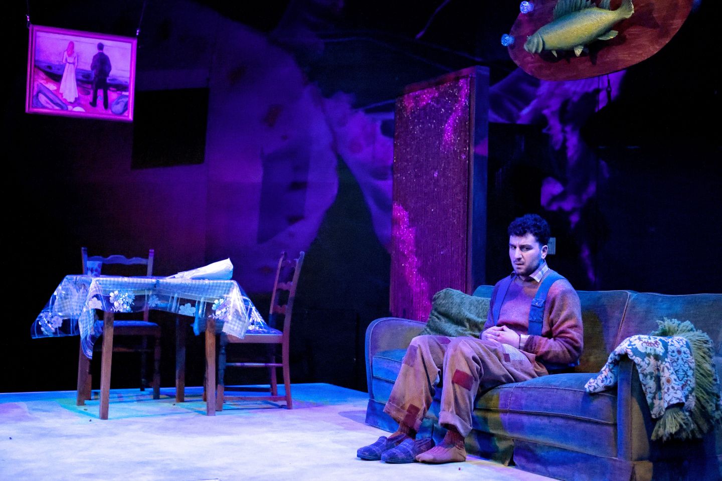 Ein Schauspieler sitzt auf einer Couch.