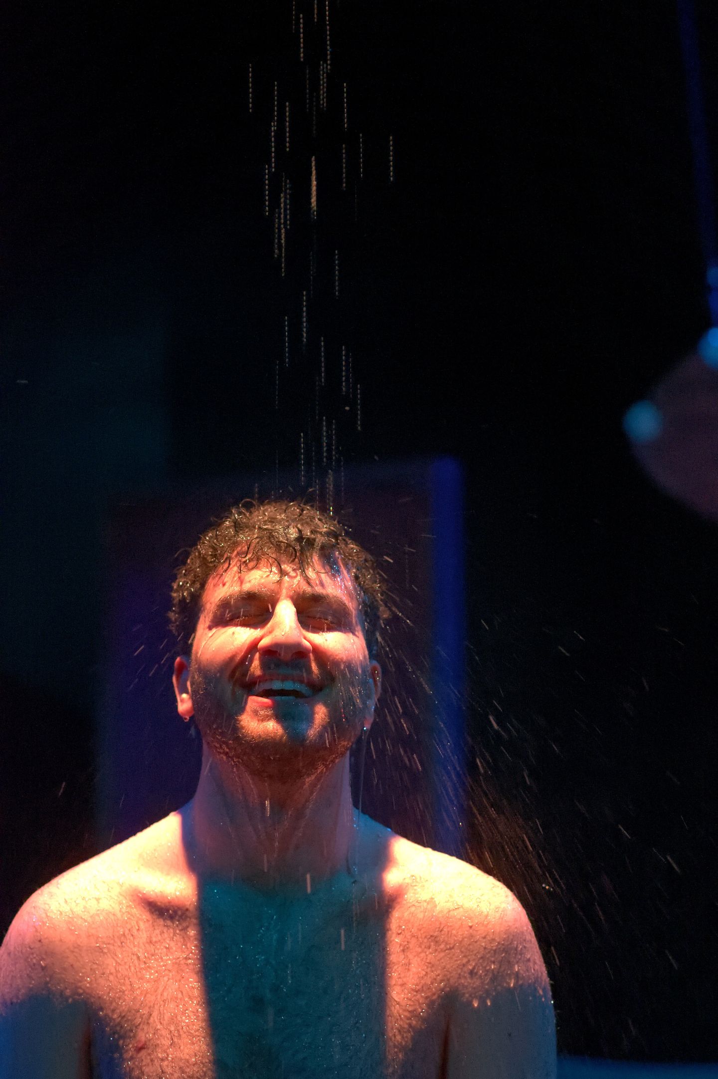 Ein Schauspieler steht unter einer Wasserdusche.