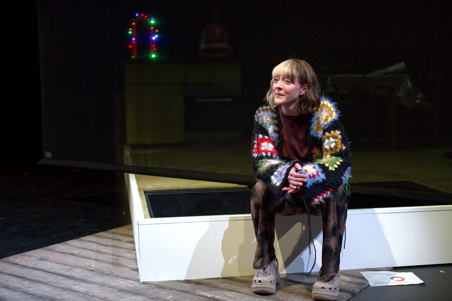 Eine Schauspielerin sitzt auf einer weissen Erhöhung.