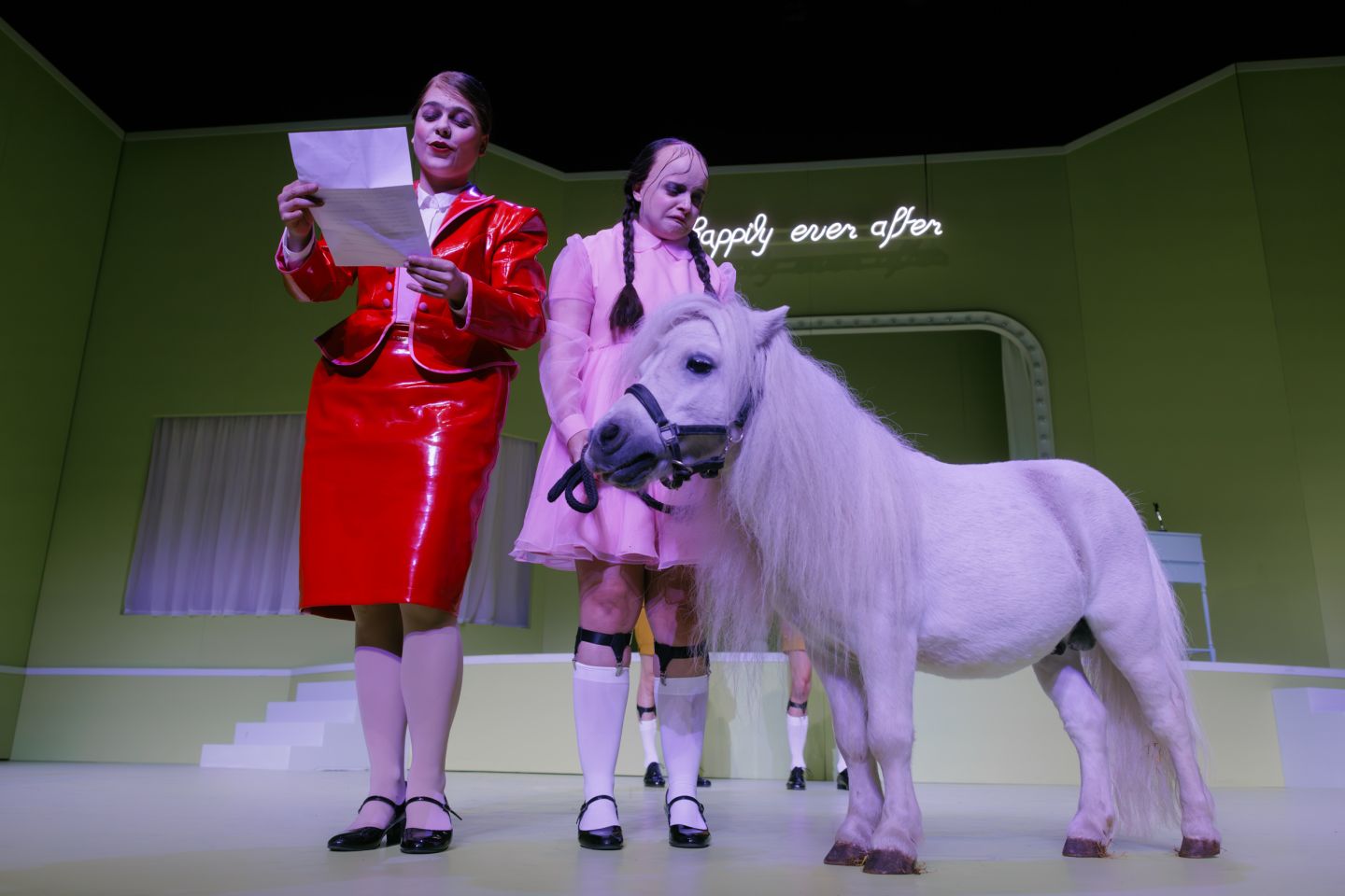 Eine Frau liest einen Brief, eine andere blickt auf ein Pony.