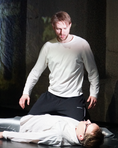 Ein Probenfoto: Ein Schauspieler kniet entsetzt neben einem anderen liegenden Schauspieler.