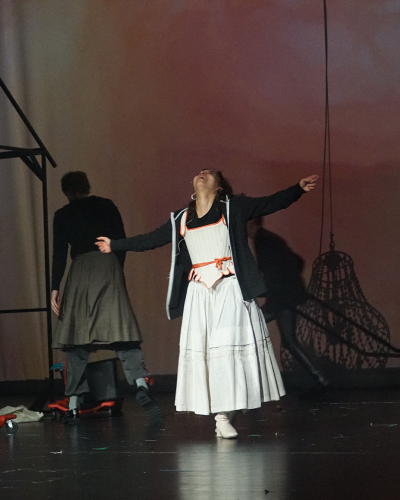 Ein Probenfoto: Eine Schauspielerin dreht sich freudig mit ausgebreiteten Armen.