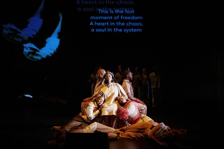 Fünf Performer sitzen im Pulk und lehnen aneinander.