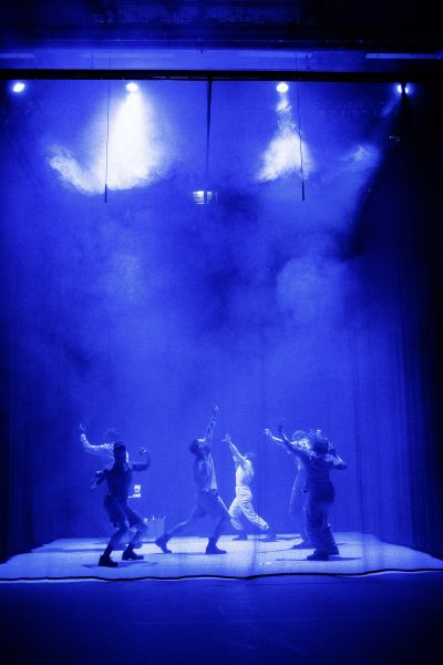 Das Bild zeigt das tanzende Ensemble in einer blauen Lichtstimmung.