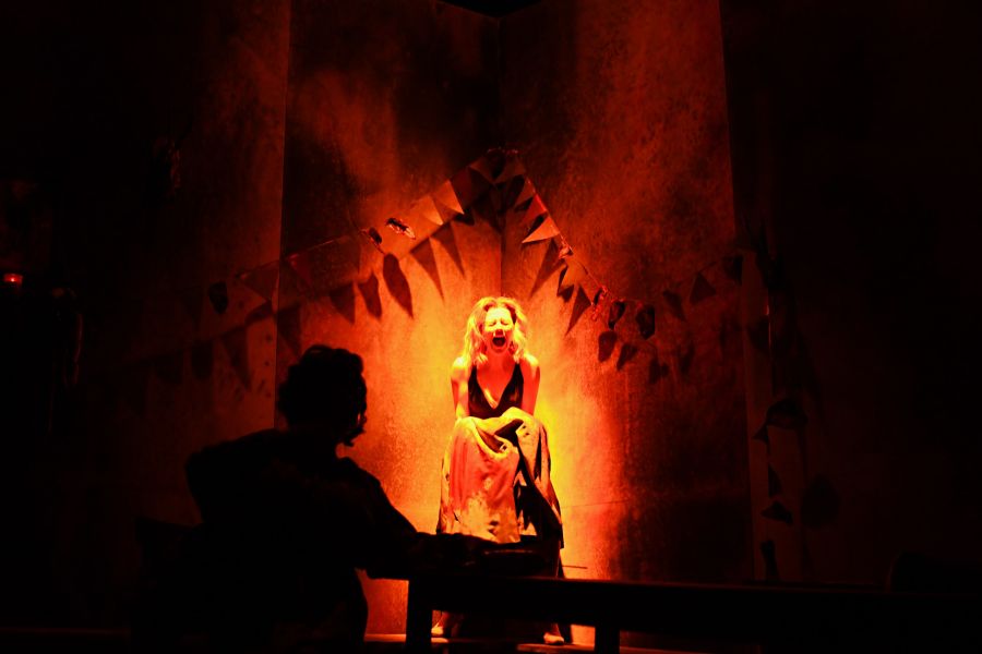 Das Bild zeigt eine schreiende Frau vor einer roten Lichtstimmung. Vorne ist die Silhouette eines Mannes zu erkennen.