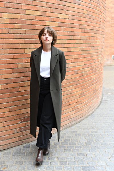 Das Ganzkörperfoto zeigt Anne Stein vor dem Volkstheatergebäude stehend