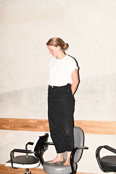 Das Ganzkörperfoto zeigt Henriette Nagel auf einem Stuhl stehend