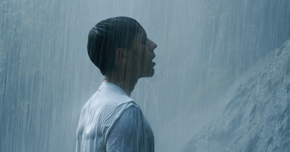 Das Foto zeigt einen Mann unter einem Wasserfall